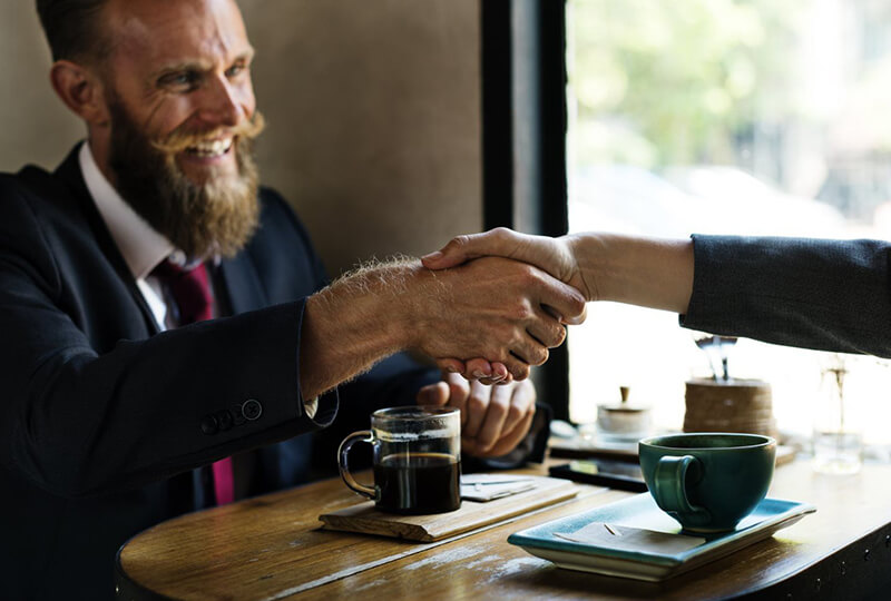 Man in suit shaking hands with colleague at coffee shop