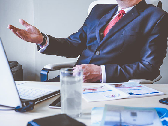 Business man sitting at his desk behind the computer talking